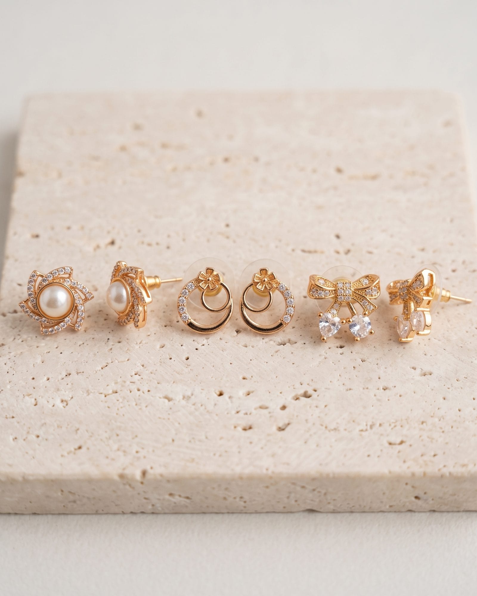 Gold-Tone AD Stone Pearl Earrings Set of 3 laid on white marble