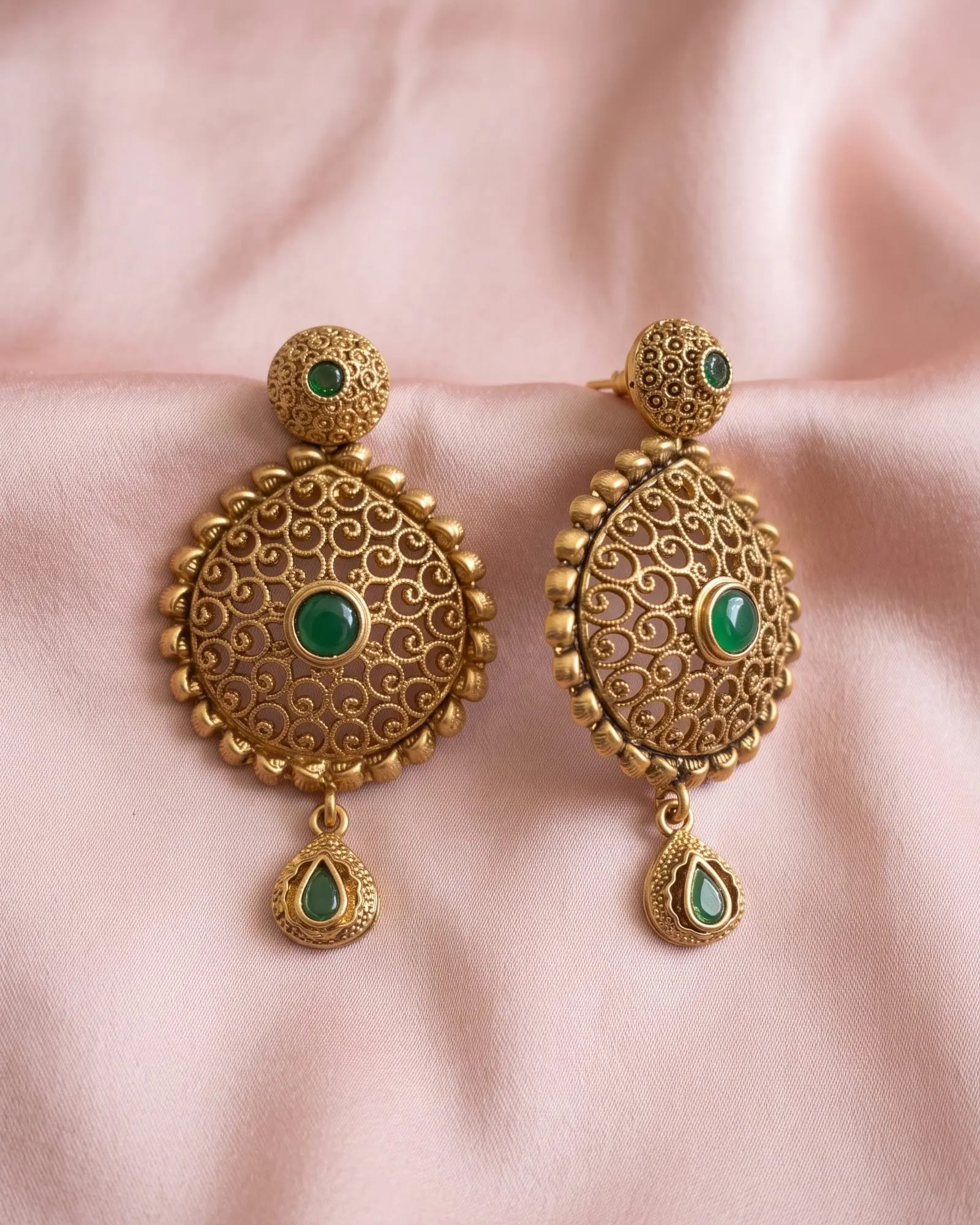 Antique Round Filigree Green Stone Earrings laid on white marble