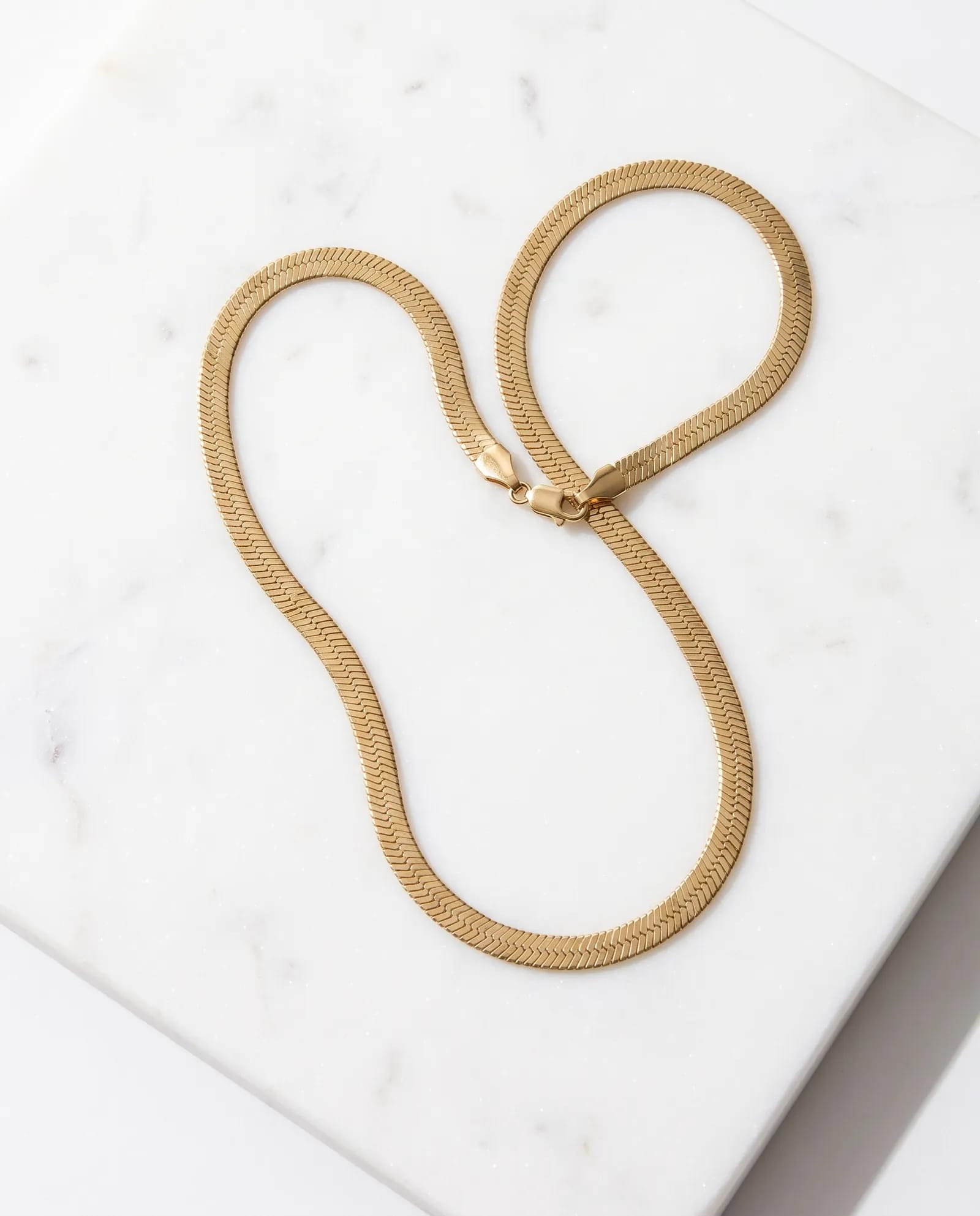 Gold-Tone Flat Snake Chain Necklace laid on white marble