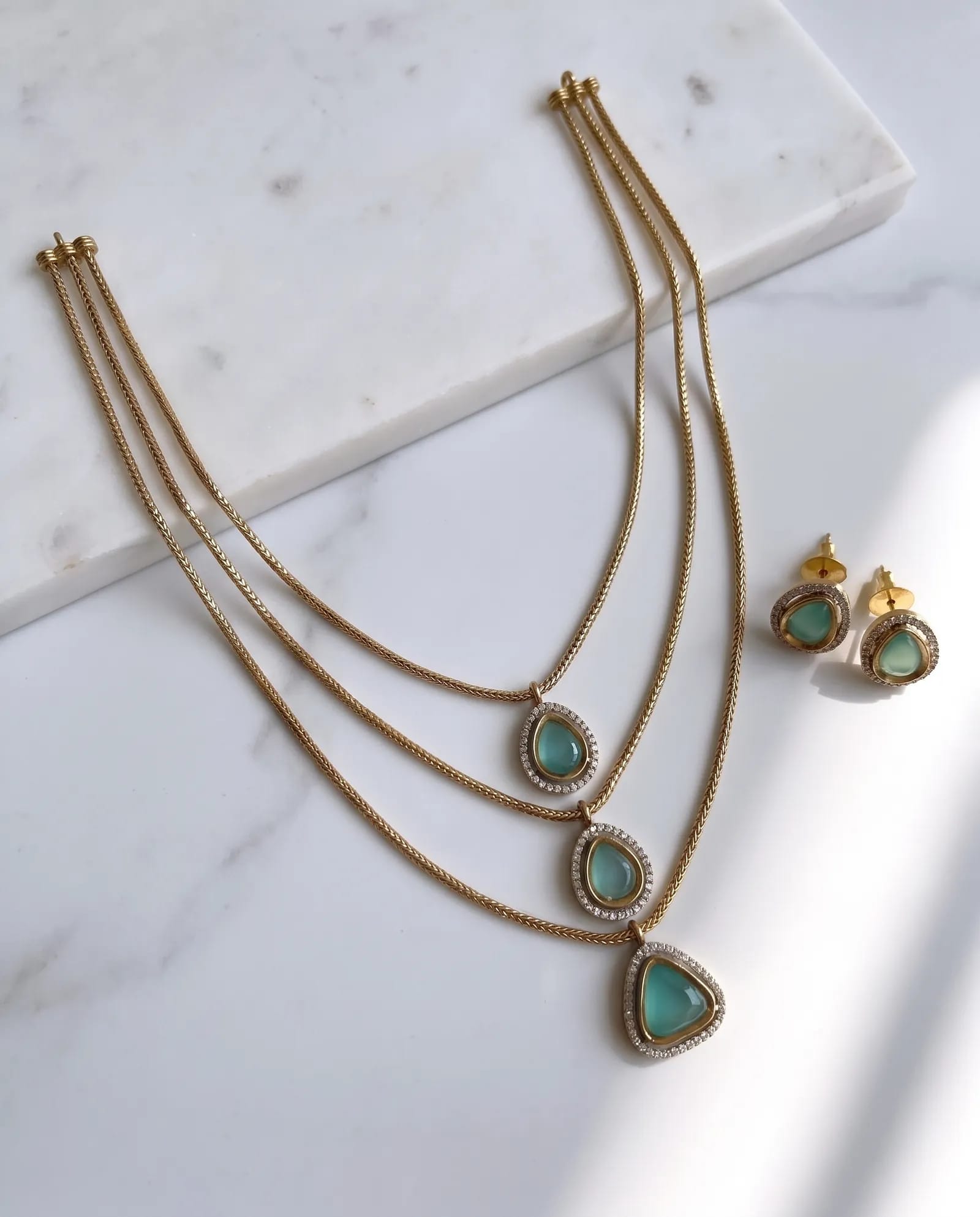 Emerald Teardrop Layer Necklace laid on white marble