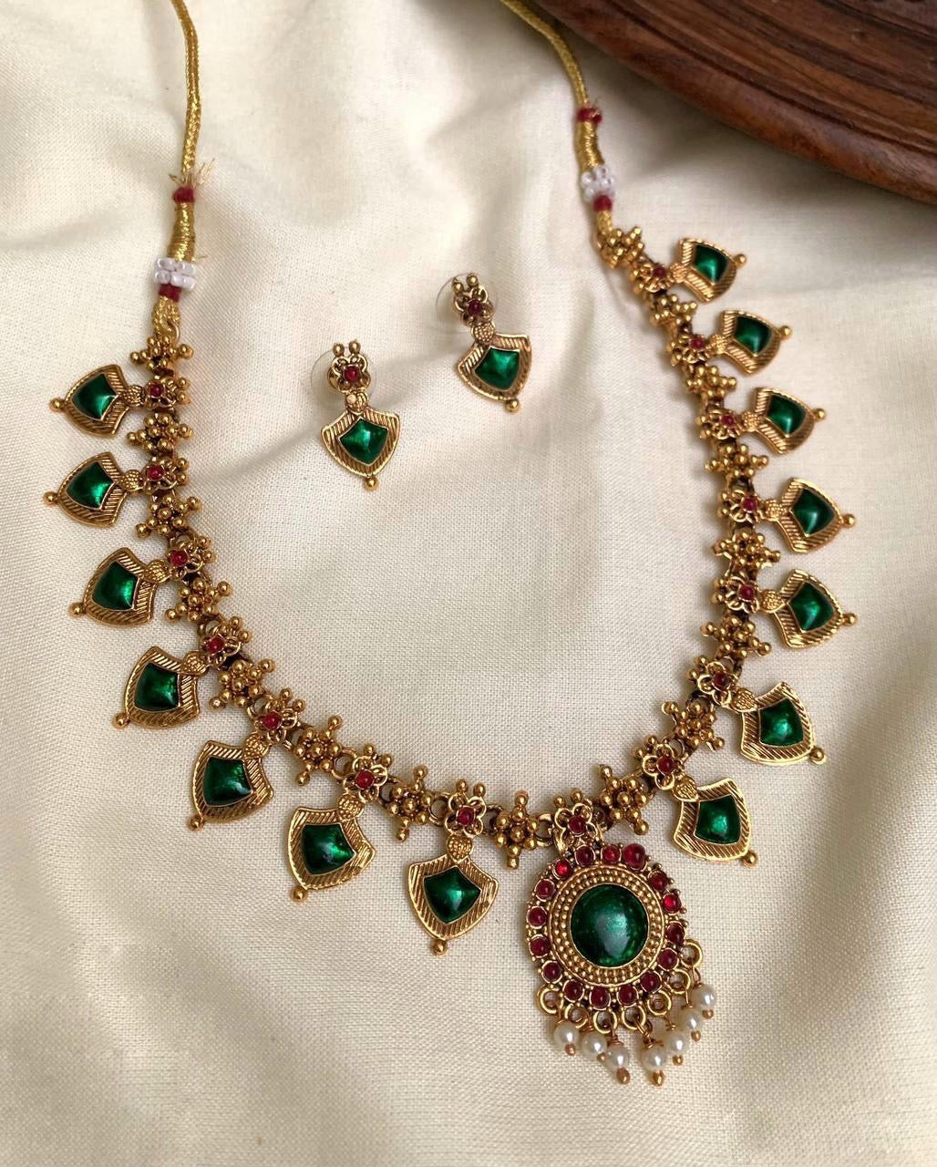 Antique gold temple necklace set with green kemp stones, ruby red accents, pearl drops, and matching earrings.